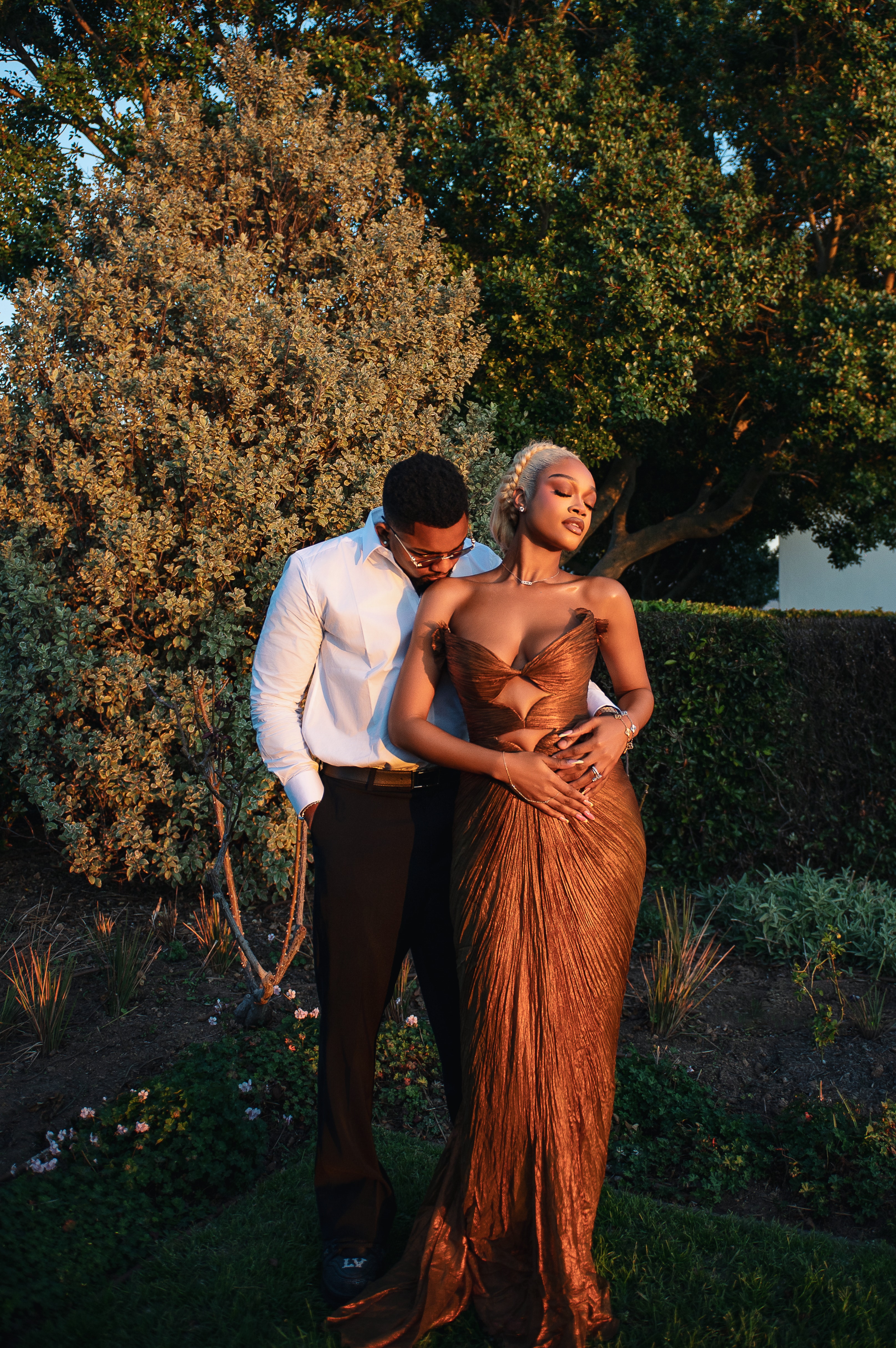 Diana and Pascal at golden hour, her in a bronze gown, his arms around her